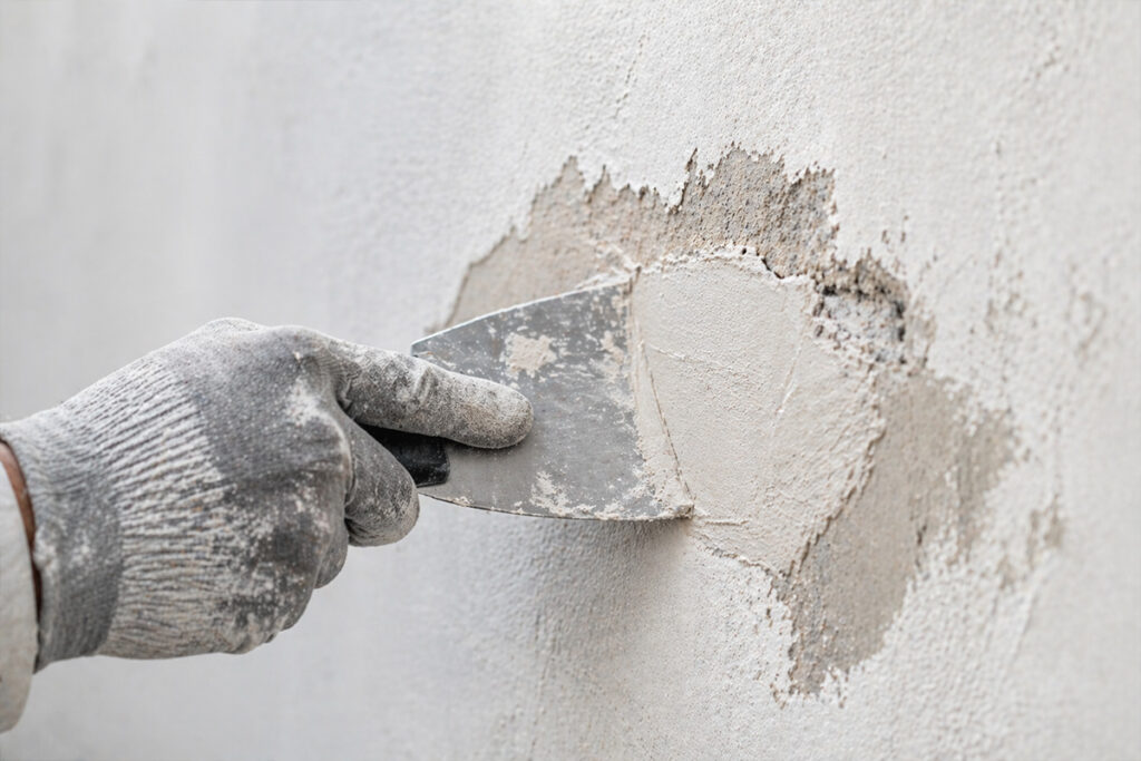 Reparatur einer beschädigten Wand mit Spachtel bei Riss und Putzschaden